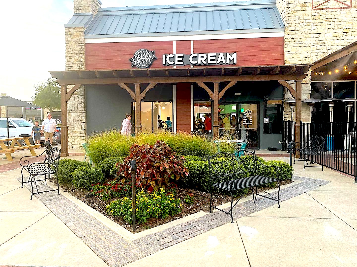 Image of Local Creamery store front with greenery and people gathering.