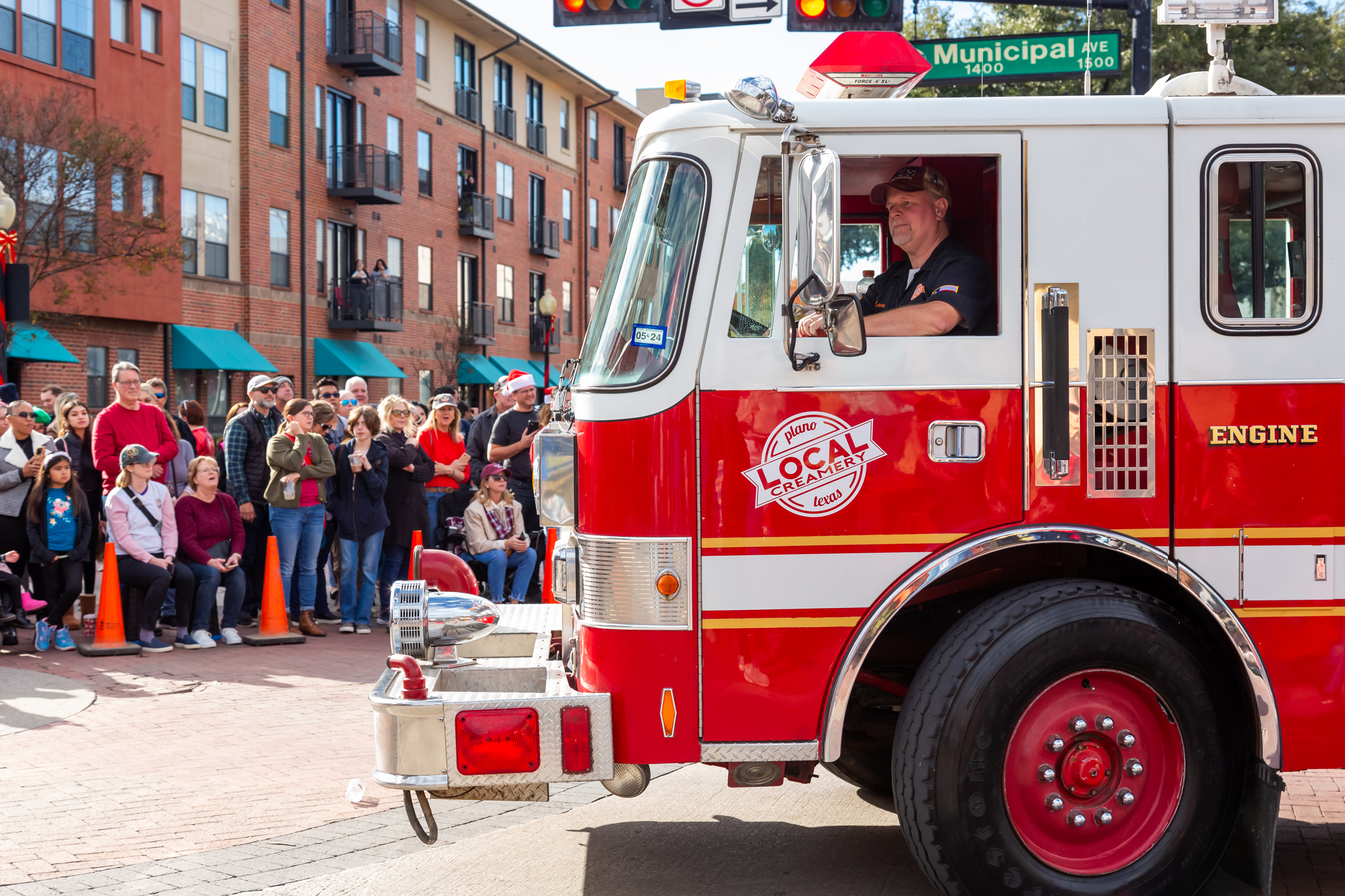 Image of Lane driving the Local Creamery ice cream truck, Big Dipper, during the Plano Holiday Parade as onlookers watch.