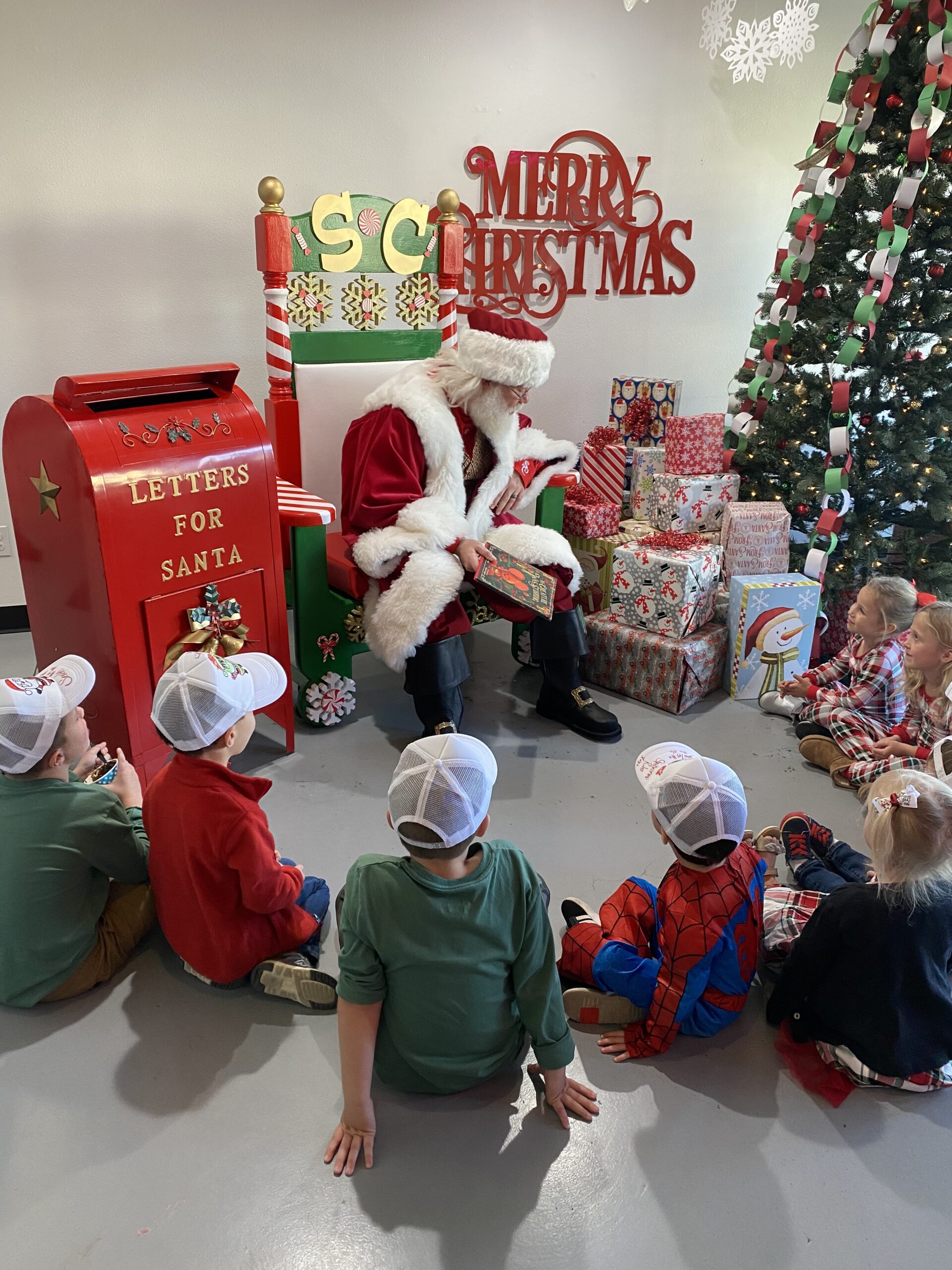 Image of kids sitting in front of Santa while he reads a book during storytime. 