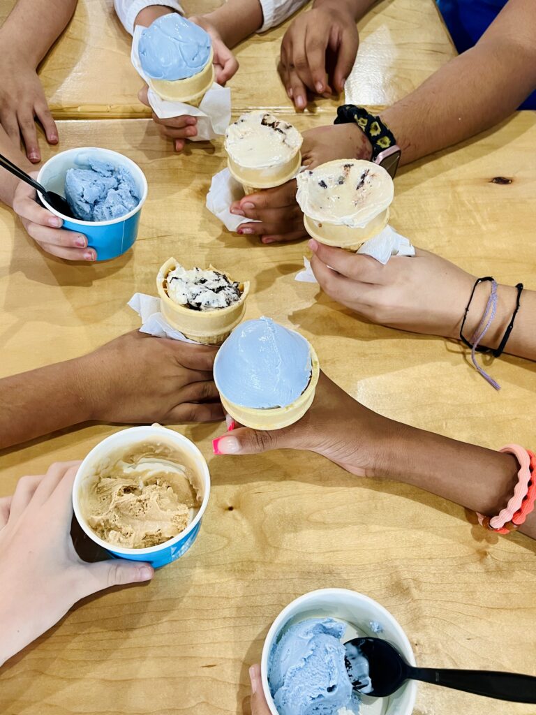 Image of different shades of hands eating ice cream cones and ice cream scoops.